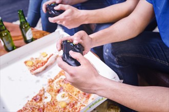 Friends eating pizza playing console