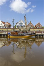 Crab cutter with reflection in the water in the harbour of Greetsiel with historic houses