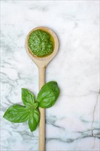 Pesto in wooden spoon and basil