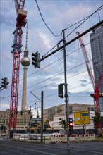 Construction cranes in front of television tower
