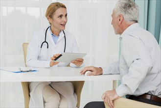 Doctor talking patient while holding tablet