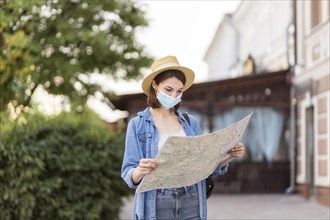 Traveller with hat medical mask checking map