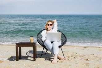 Front view woman with laptop working beach with cup coffee