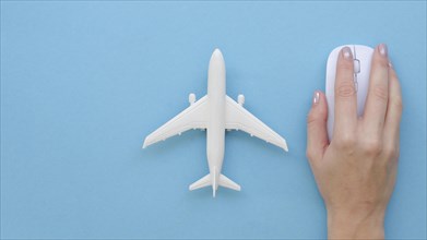 Hand with mouse beside airplane toy