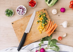 Overhead view chopping board with knife vegetables wooden desk
