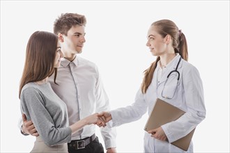 Friendly medic handshaking with couple