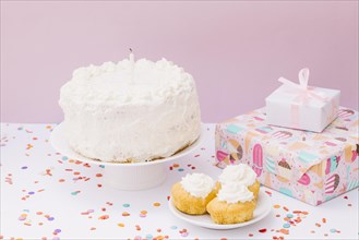 Birthday cake muffins gift boxes with confetti white desk against pink background