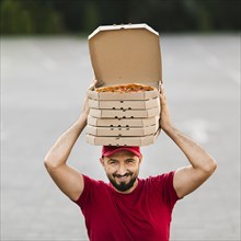 Front view delivery guy with pizza boxes his head