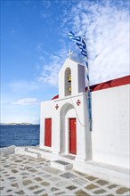 Small white Cycladic chapel on the coast
