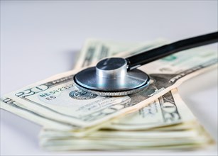 Close up of medical stethoscope on dollar bills isolated. Medical health cost concept