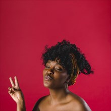 Attractive nude african young woman showing peace sign studio with bright background