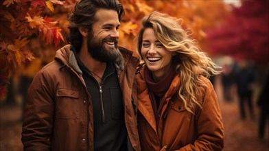 Warmly dressed young loving couple laugh as they enjoy the beautiful fall leaves in the park