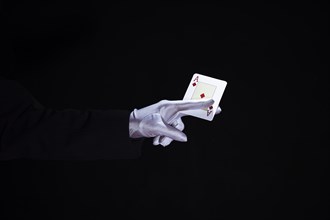 Magician holding aces playing card fingers against black background