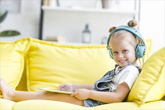 Smiling cute little girl headphones listening music using tablet