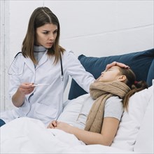 Female doctor measuring temperature her sick patient lying bed