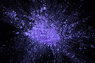 Overhead view purple color exploding dark surface