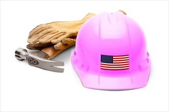 Pink hardhat with an american flag decal on the front with hammer and gloves isolated on white background