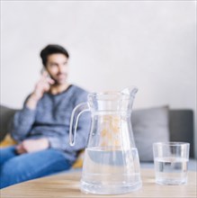 Glass jug near man with smartphone