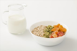 Milk with healthy bowl muesli pumpkin seeds dry fruits white bowl white background