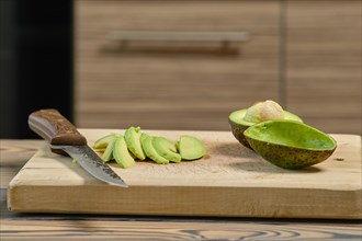 Thin slices of fresh avocado on wooden cutting board