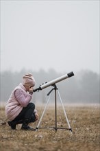 Side view kid using telescope outside