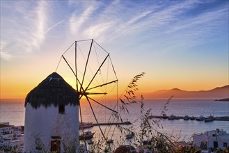 Famous traditional white windmill overlook civil port and harbor of Mykonos