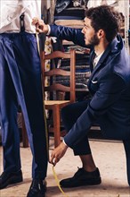 Fashion designer taking measurement male customer s pant shop