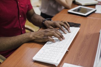 Crop black man typing keyboard