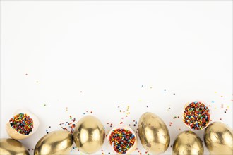Eggshells with sprinkles near golden eggs