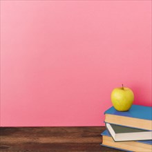 Apple books near pink wall