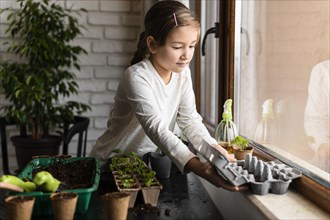 Young girl planting seeds by window