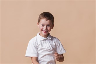 Smiling innocent boy beige backdrop