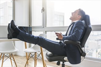Happy businessman sitting chair workplace using mobile
