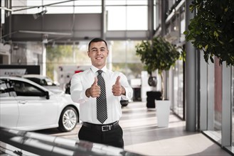 Front view male car dealer showing ok sign