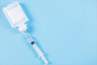 Syringe inserted normal saline solution plastic bottle blue background