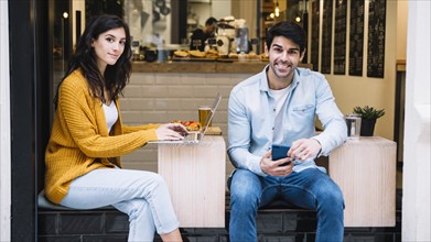 Hispanic couple with electronic devices cafe
