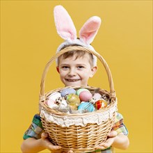 Little boy holding basket with painted eggs