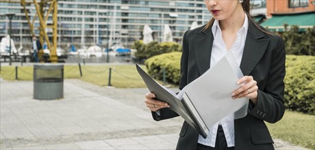 Close up young businesswoman reading folder outdoors