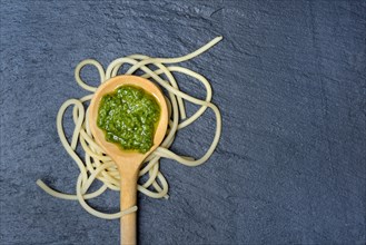 Pesto in cooking spoon and spaghetti