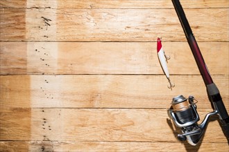 Fishing rod with red white fishing bait wooden plank
