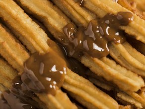 Close up fried churros with melted chocolate