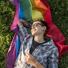 Cheerful young person lying lgbt flag park
