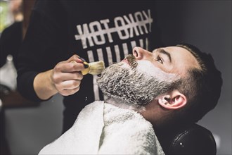 Unrecognizable barber putting foam client