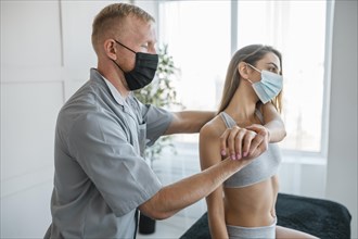 Physiotherapist wearing medical mask during therapy session with female patient