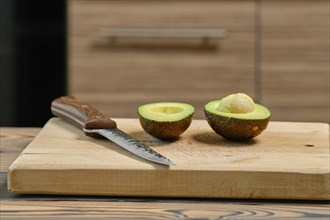 Fresh avocado cut on half on wooden cutting board
