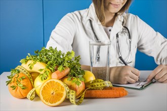 Female dietician writing clipboard with fresh fruits desk