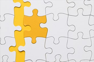 High angle view yellow puzzle piece arranged with white pieces