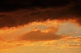Cloudy sky at sunset. The sky is visible through a gap in the clouds. The image conveys a mood of an impending storm or bad weather