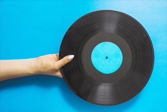 Overhead view female hands holding vinyl record blue background