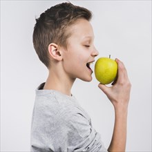 Side view boy eating green fresh apple isolated white background